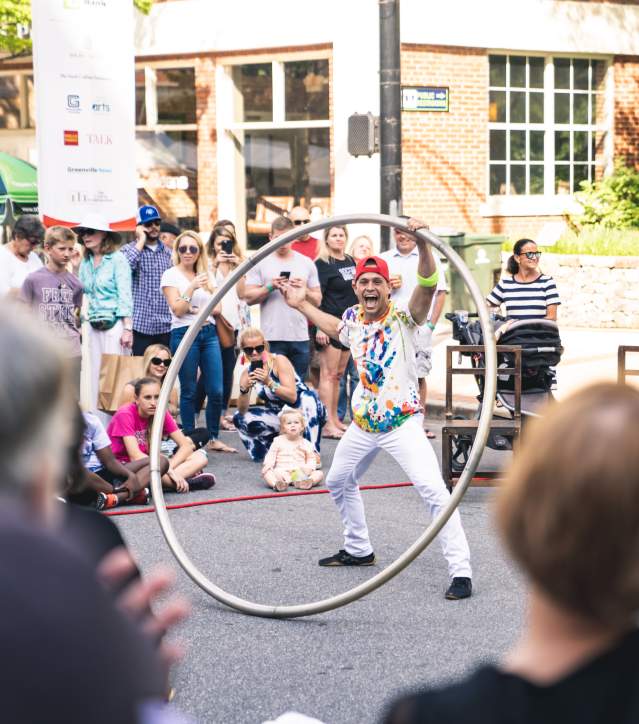 Street performers showcasing their talents on Main Street during Artisphere, with a lively crowd gathered to watch and enjoy the festival atmosphere.