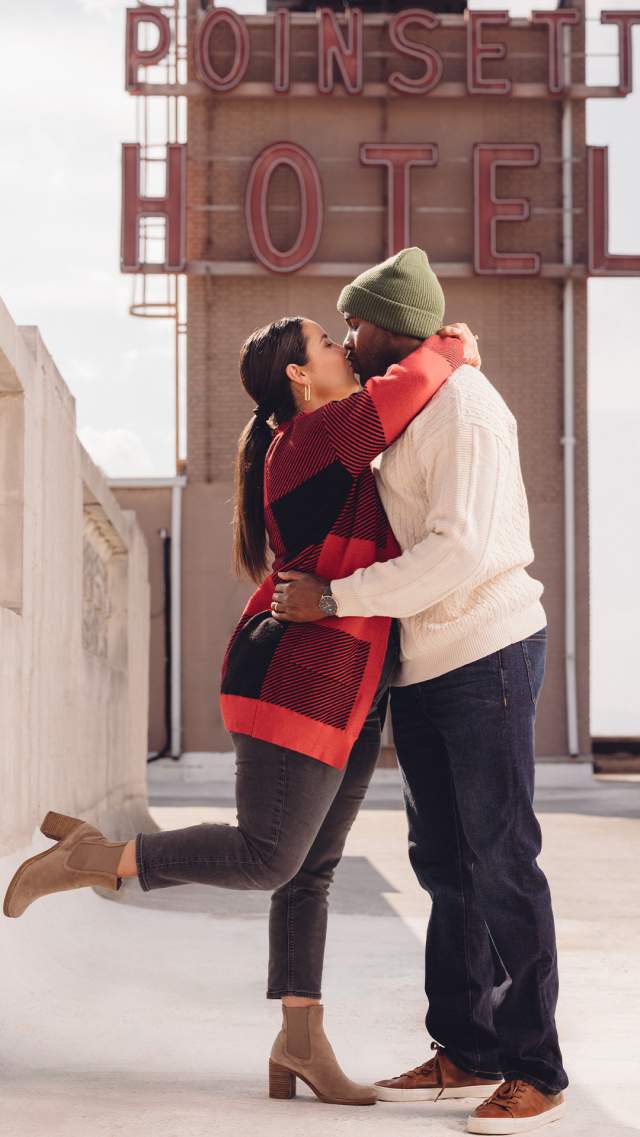 A man and woman kissing on the rooftop of the Westin Poinsett hotel during winter.