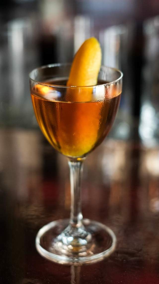 A mixed drink with orange sits atop the bar at Swordfish Cocktail Club in downtown Greenville, SC.