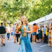 A female shopper walks the length of the TD Saturday Market with Stecca bread and fresh flowers in downtown Greenville, SC.