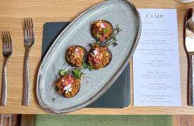 Overhead view of a plated dish of small bites and place setting with menu at CAMP.