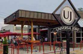 Exterior view of Universal Joint outdoor patio with covered seating and red patio umbrellas