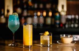 Four mixed drinks sit atop a bar counter at The Press Room speakeasy in downtown Greenville, SC.