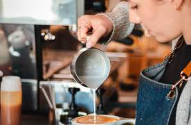 A barista designs art in the foam of a latte at Unlocked Coffee Roasters in the Village of West Greenville, SC.
