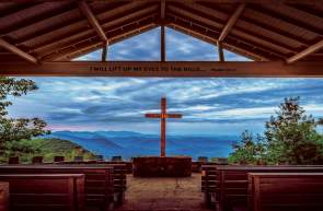 Pretty Place Chapel in Cleveland, South Carolina.  Cross and pews in the focus and the Blue Ridge Mountains in the background.
