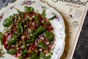 Plate of tartare on a plate and Scoundrel menu laying underneath it.