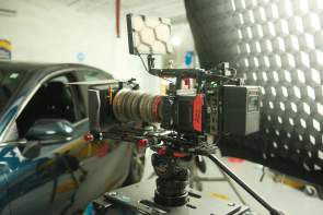 Camera pointed at a car on the driver's side door area inside a film studio