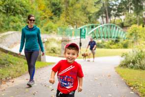 A child and his mother stroll and play on the GHS Swamp Rabbit Trail in Cleveland Park.