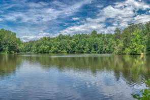 A lake with the reflection of the trees and blue sky at Paris Mountain State Park.