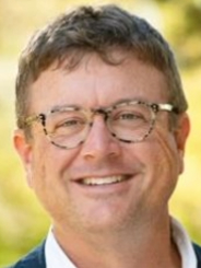 Closeup headshot of Matt Storm focusing on his head from the neck up with a yellowish green blurred nature background
