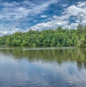 A lake with the reflection of the trees and blue sky at Paris Mountain State Park.