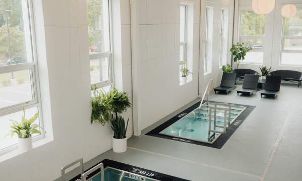 Interior of Sauna House cold plunge pools in a bright white room with lots of windows and natural light, plus ambient lighting above.