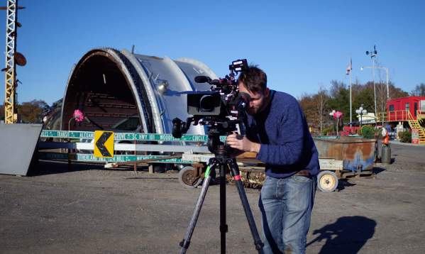 Man filming with camera equipment outdoors at an industrial environment