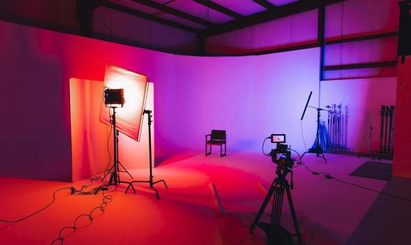 Red and purple lights creating a gradient background for photographers at the studio space at Kings Collective with camera equipment and a chair for a subject to sit.