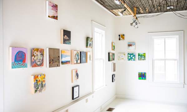 A bright, airy gallery space with contemporary art displayed against white walls.