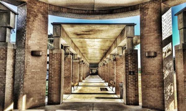 A stone tunnel-like walkway at Greenville Memorial Hospital, with light filtering through the open sides and a smooth pathway leading through.