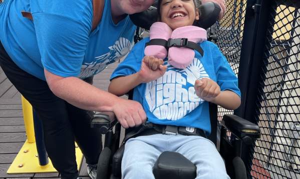 Woman smiling next to youth in wheelchair on accessible playground at The Children's Museum of the Upstate in Greenville, SC.