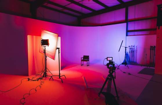 Red and purple lights creating a gradient background for photographers at the studio space at Kings Collective with camera equipment and a chair for a subject to sit.