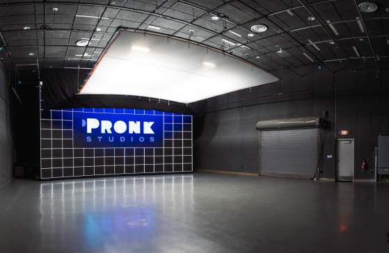 A 3,000 sq. ft. studio at Pronk Studios with an LED light wall as the background showcasing the Pronk logo and bright overhead lights with a ceiling light diffuser to make it less harsh on subjects below.