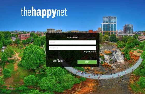 The Happy Net login screen with an aerial image of Falls Park on the Reedy in the background and a black box to enter a user's email and password and a green login button.