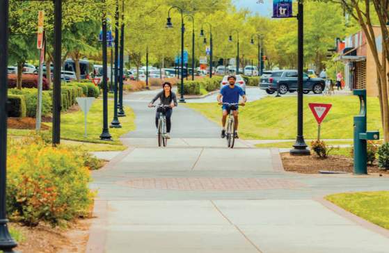 Two bikers cycling along the Prisma Health Swamp Rabbit Trail in downtown Travelers Rest, SC.