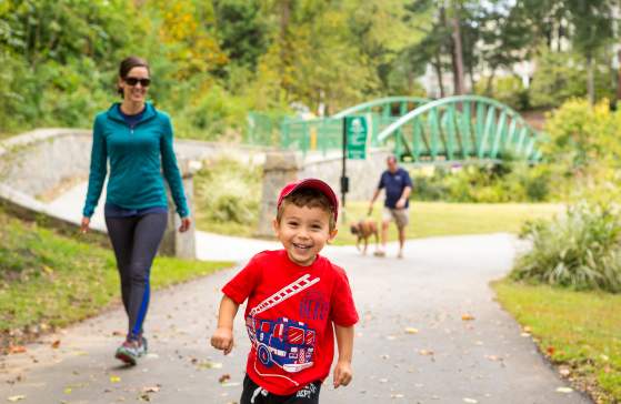 A child and his mother stroll and play on the GHS Swamp Rabbit Trail in Cleveland Park.