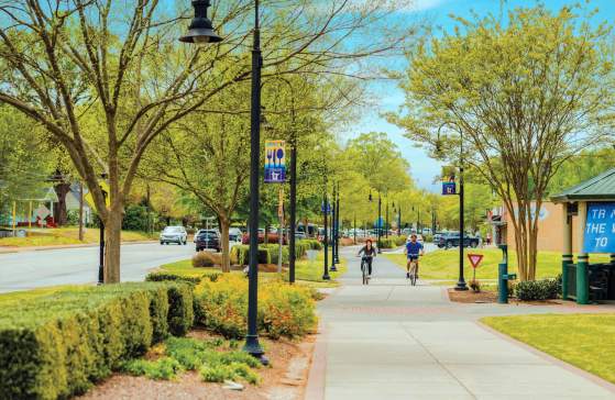 Two bikers cycling along the Prisma Health Swamp Rabbit Trail in downtown Travelers Rest, SC.
