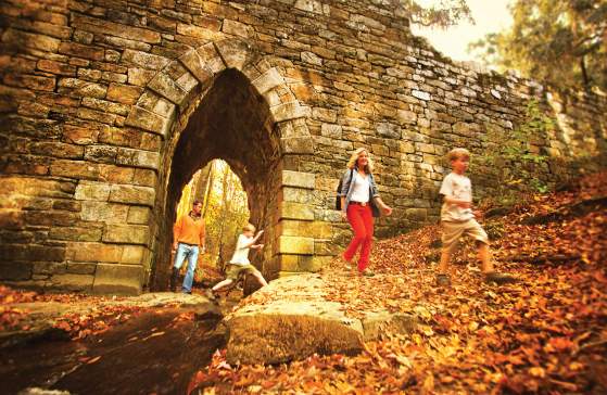 Walkers on a trail walking through the arch at the Poinsett Bridge in Greenville, SC.