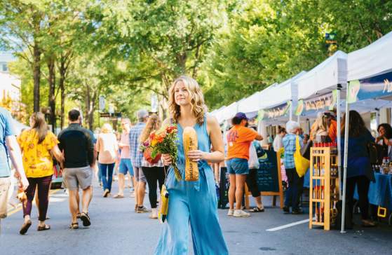 A female shopper walks the length of the TD Saturday Market with Stecca bread and fresh flowers in downtown Greenville, SC.
