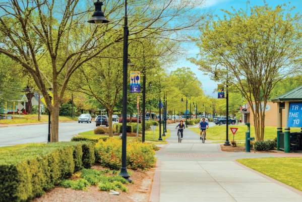 Two bikers cycling along the Prisma Health Swamp Rabbit Trail in downtown Travelers Rest, SC.