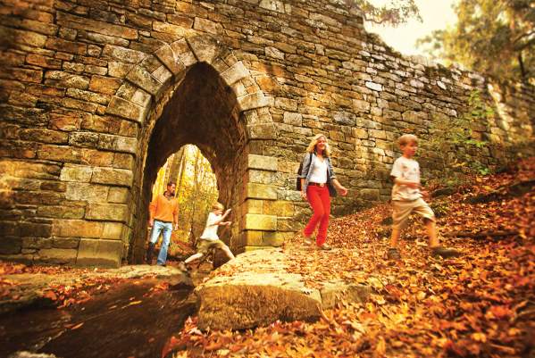 Walkers on a trail walking through the arch at the Poinsett Bridge in Greenville, SC.