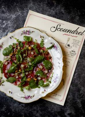 Plate of tartare on a plate and Scoundrel menu laying underneath it.