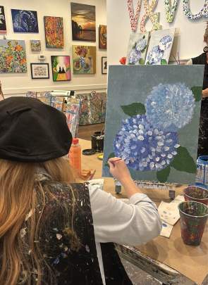 Woman painting hydrangeas at Vino & Van Gogh