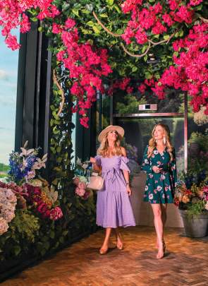 Two beautifully dressed women walk into the floral-themed entryway of Juniper, a rooftop bar and restaurant in downtown Greenville, SC.