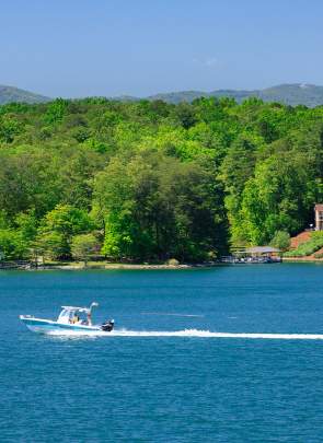 Boater pulling wakeboarder on a sunny day on Lake Keowee.