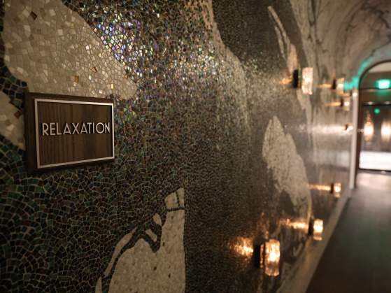 Poseidon Spa hallway, dimly lit with light reflecting off the metallic tile mosaic on the wall.