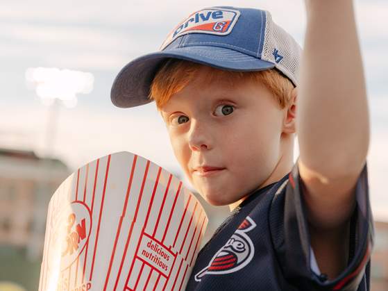 A boy gives a thumb's up with his popcorn at a Greenville Drive baseball game in Greenville, SC.