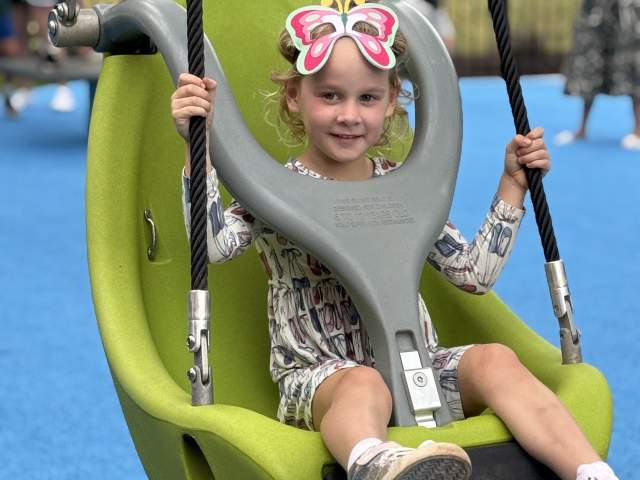 Young girl in an adaptive swing at Brooks Playground.