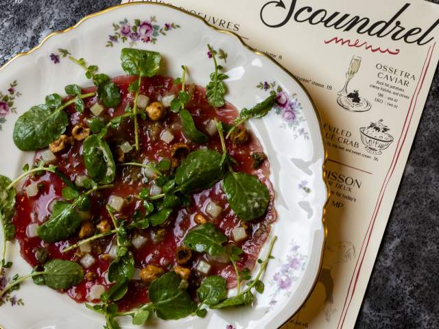 Plate of tartare on a plate and Scoundrel menu laying underneath it.