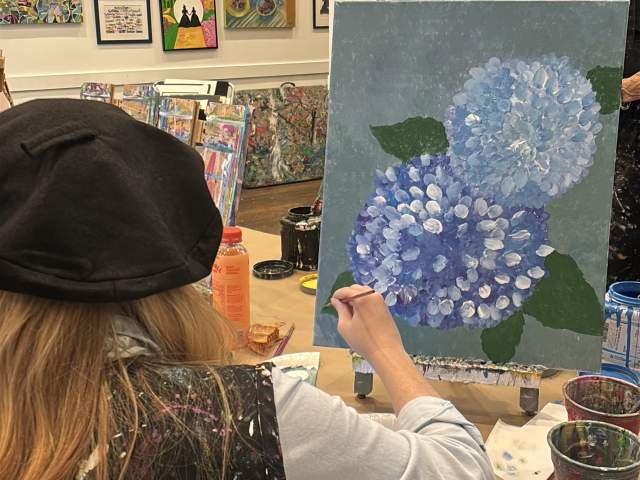 Woman painting hydrangeas at Vino & Van Gogh