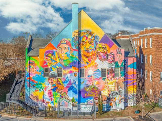 Aerial view of a building with a stunning, bright and colorful mural featuring the faces of eight Greenvillians that experienced homelessness.
