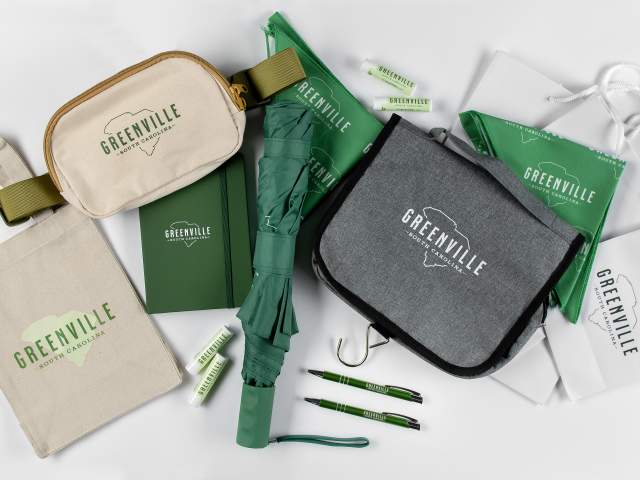 Assortment of Greenville branded merchandise including a tote bag, an umbrella, a journal, pens and more!