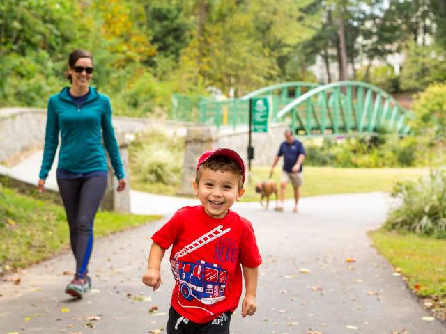 A child and his mother stroll and play on the GHS Swamp Rabbit Trail in Cleveland Park.