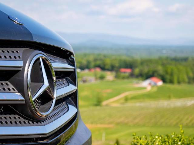 Front of a black van sitting on hill near lush green fields