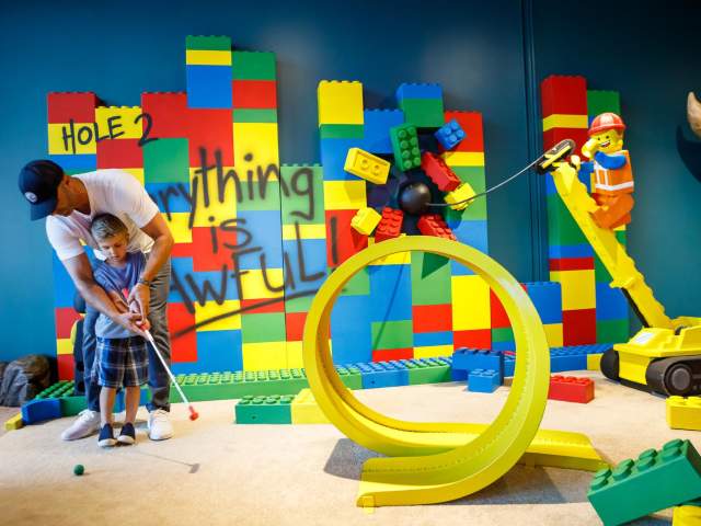 A father and son play mini golf on the Lego Movie-inspired hole at Group Therapy Pub & Playground in downtown Greenville, SC.