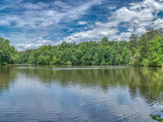 A lake with the reflection of the trees and blue sky at Paris Mountain State Park.