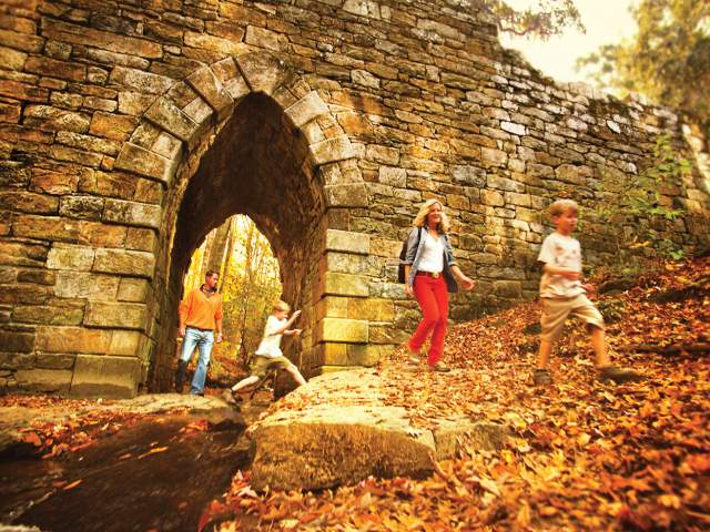 Walkers on a trail walking through the arch at the Poinsett Bridge in Greenville, SC.