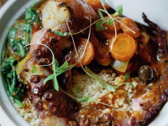 Moroccan magic: Octopus Tagine meets couscous, sun-dried tomatoes, spinach, Niçoise olives, carrots, and a sprinkle of za'atar enchantment at Oak & Honey in downtown Greenville, SC.