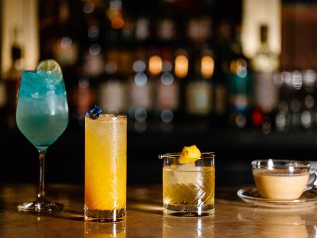Four mixed drinks sit atop a bar counter at The Press Room speakeasy in downtown Greenville, SC.
