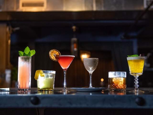 A host of mixed drinks sits atop a bar counter at speakeasy Vault & Vator in downtown Greenville, SC.